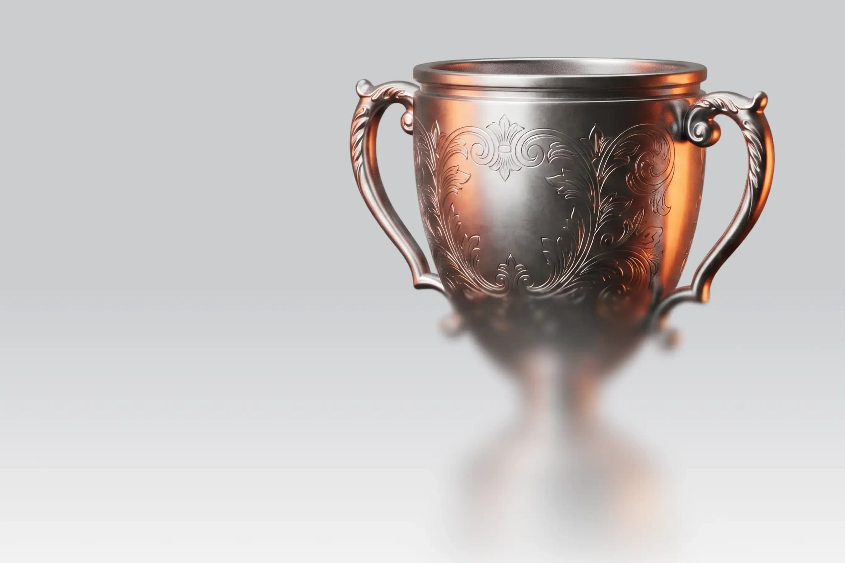 An ornate silver trophy cup with intricate details on a light grey background.