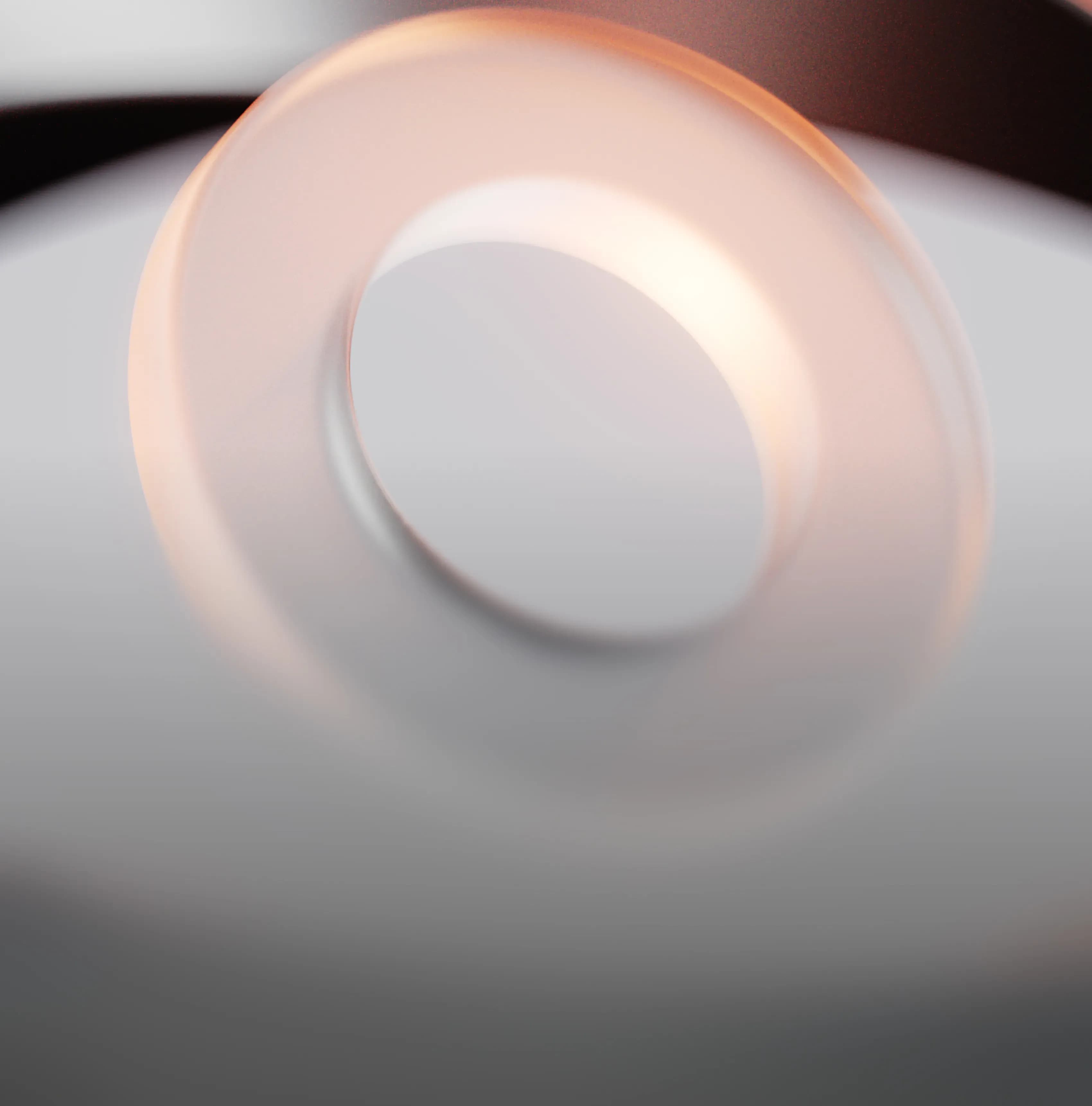 A translucent, glowing ring or torus shape on a reflective gray surface.