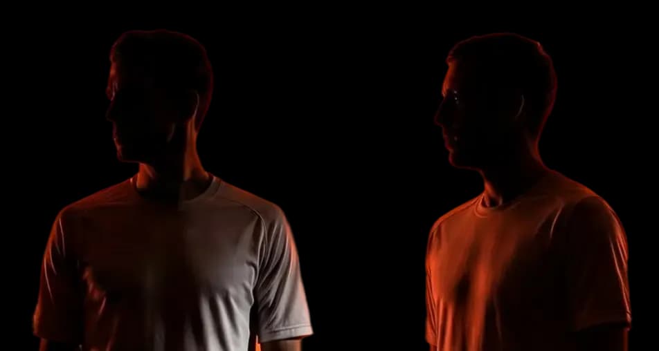 Two men in silhouette illuminated by dramatic orange light against a black background.