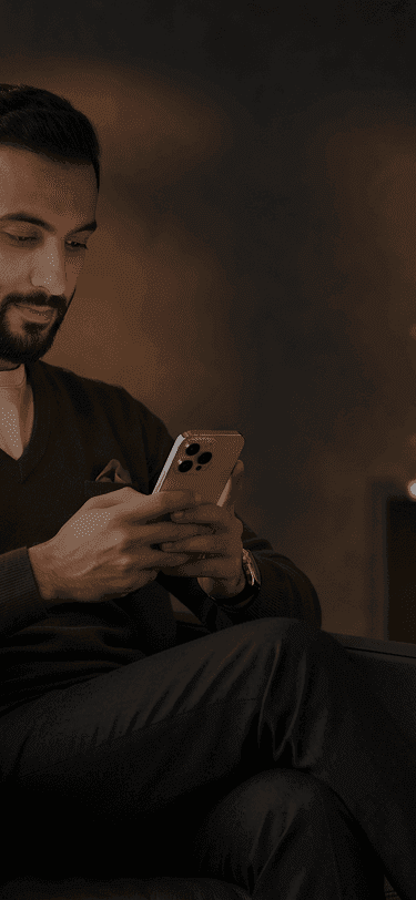 Bearded man in a dark sweater engrossed in his smartphone in a modern setting.