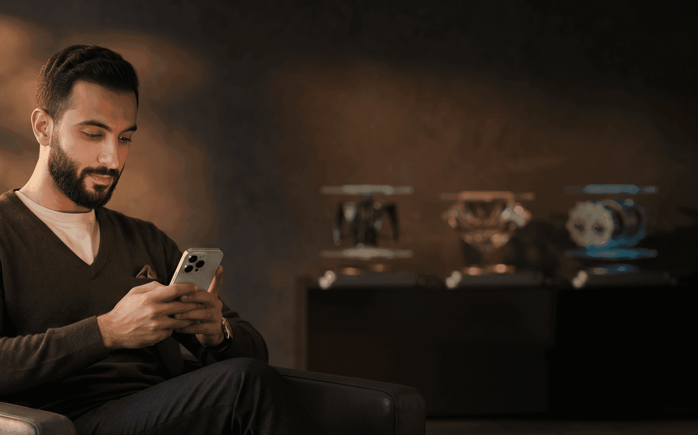 Bearded man in a dark sweater engrossed in his smartphone in a modern setting.